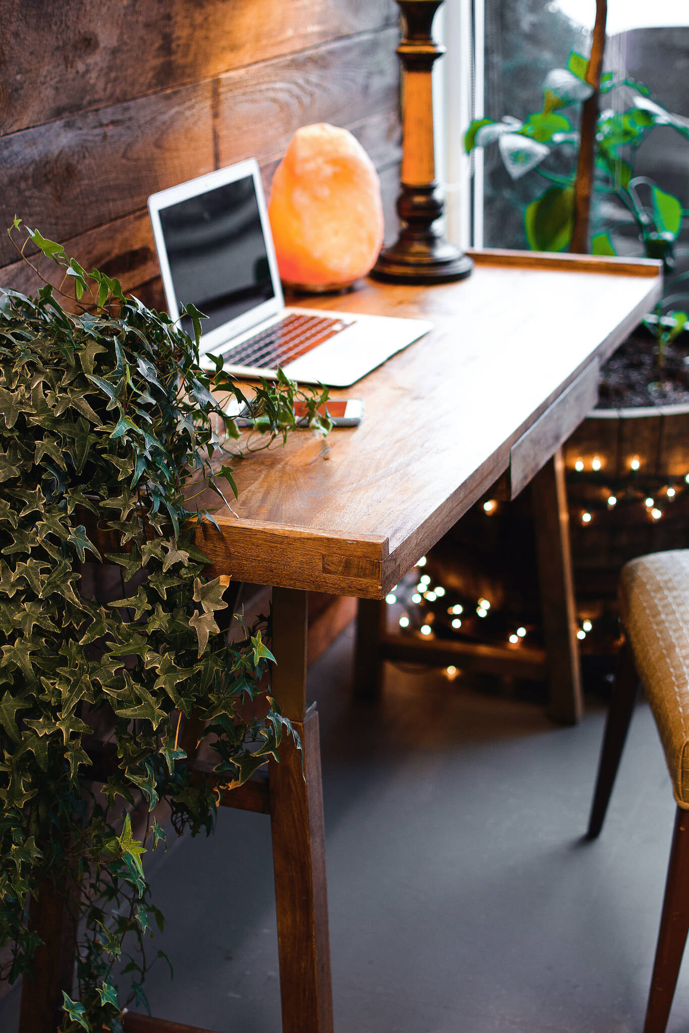 A wooden desk with a laptop and a salt lamp